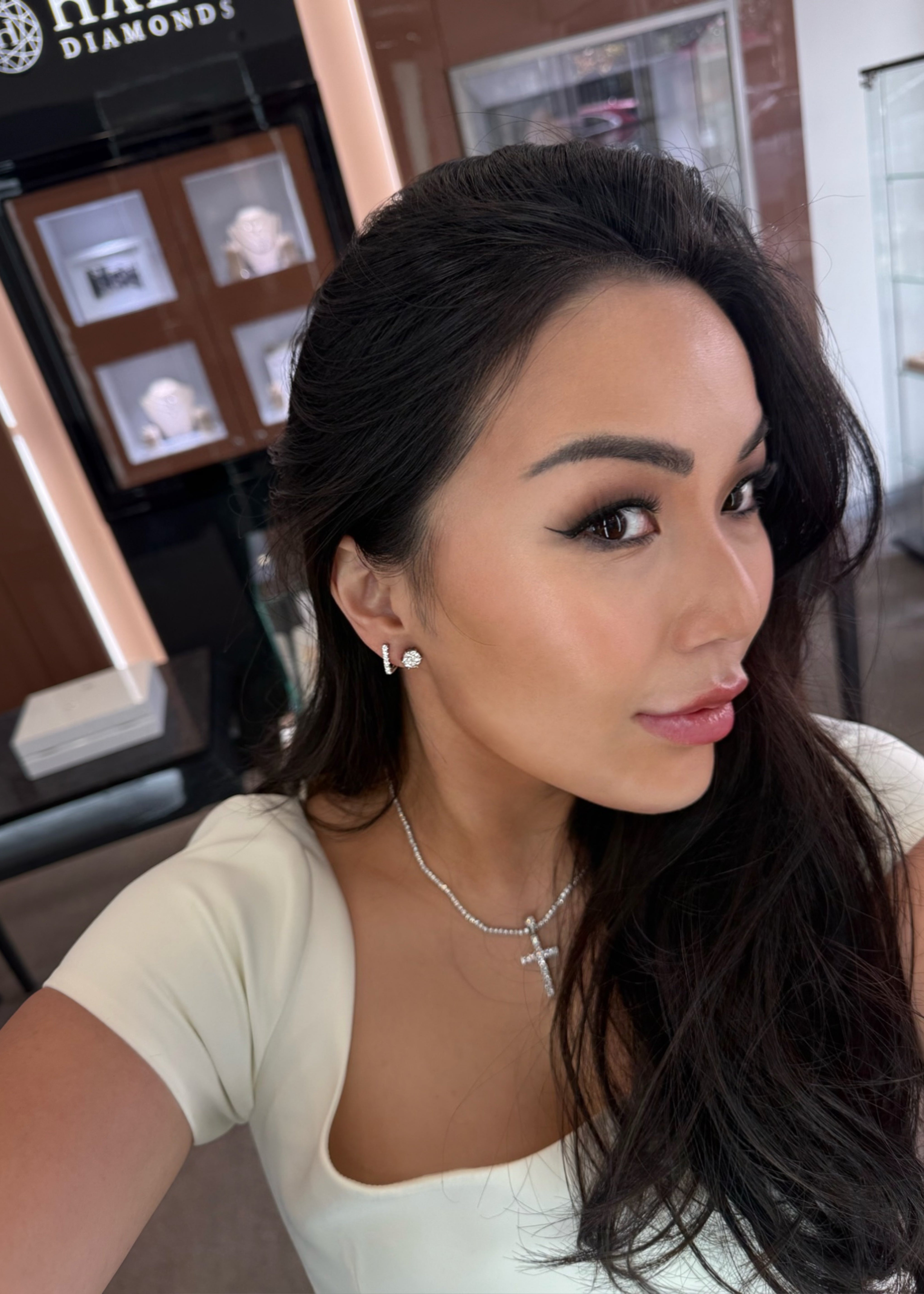Woman with dark hair and earrings in a jewelry store setting